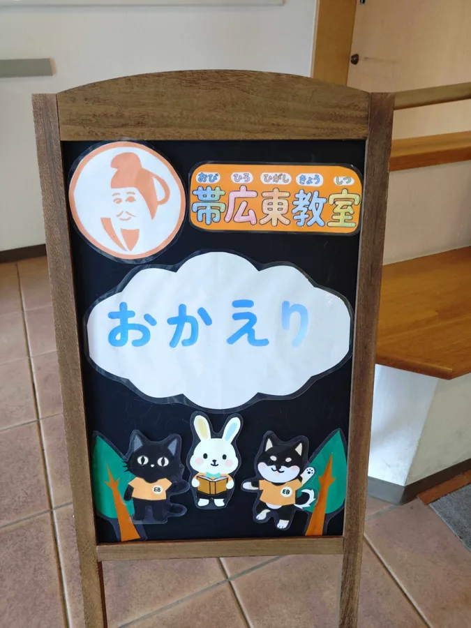 しょうとくクラブ帯広東教室の「おかえり」看板 — キャラクターで迎える玄関