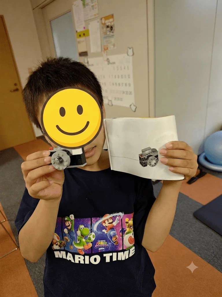 帯広東教室 LEGO 創作 — 完成した LEGO カメラを誇らしげに掲げる子ども